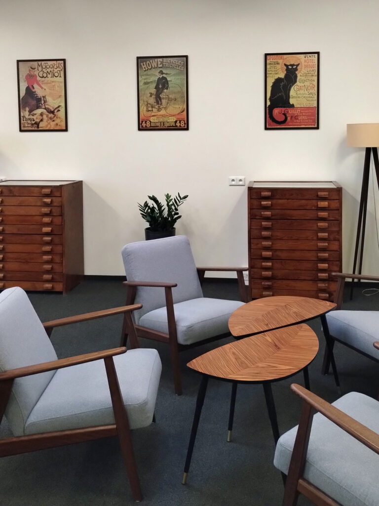 Sala Pracowników Naukowych - na środku trzy fotele przy stoliku. Przy ścianie szafki, kwiat doniczkowy oraz lampa. Na ścianie plakaty w ramkach.