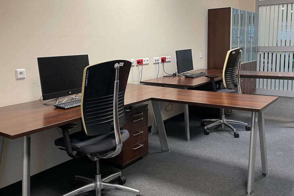 Sala Pracowników Naukowych nr 4.09 - dwa stanowiska pracy dla czytelników. Stoły z krzesłami i szafkami. Na stołach komputery.